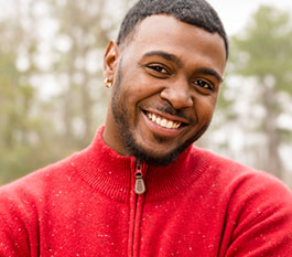 Man in red sweater smiling after cosmetic dentistry