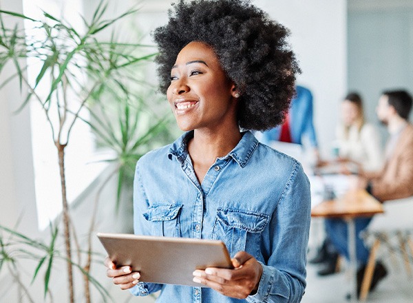 Woman smiling while holding tablet in office