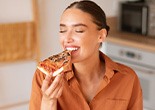 Woman enjoying slice of pizza at home