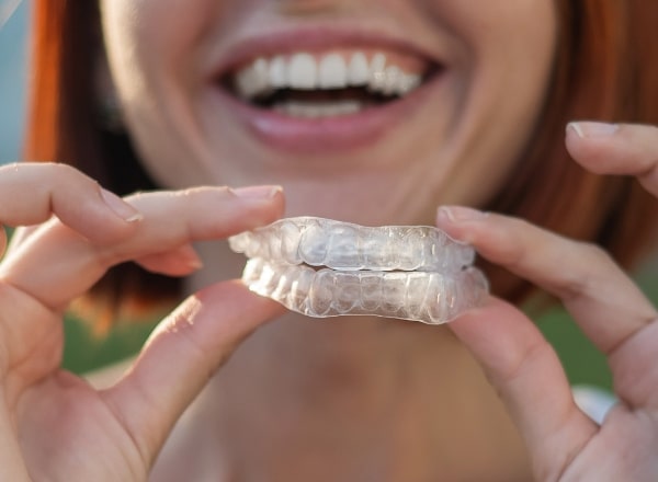 Patient holding up a set of nightguards for teeth grinding