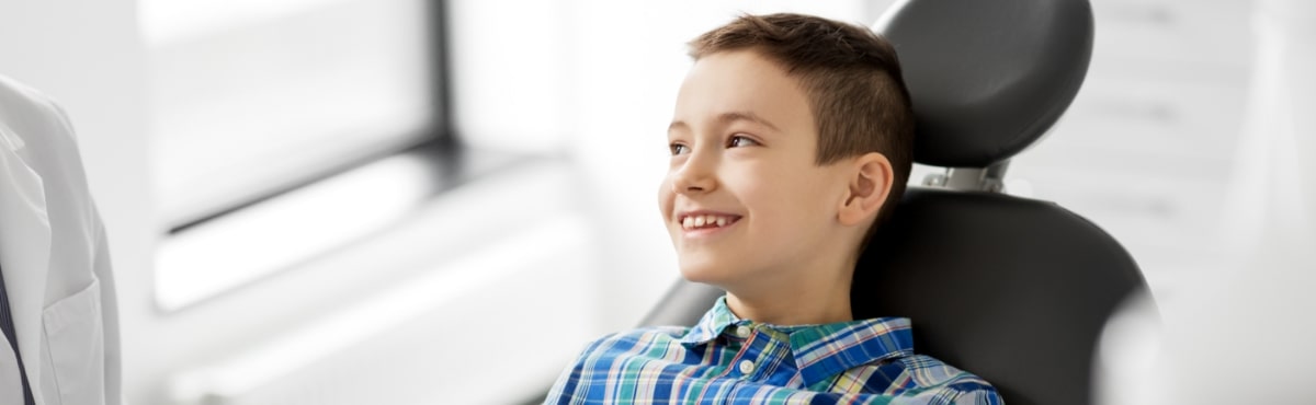 Child in dental chair smiling during children's dentistry visit