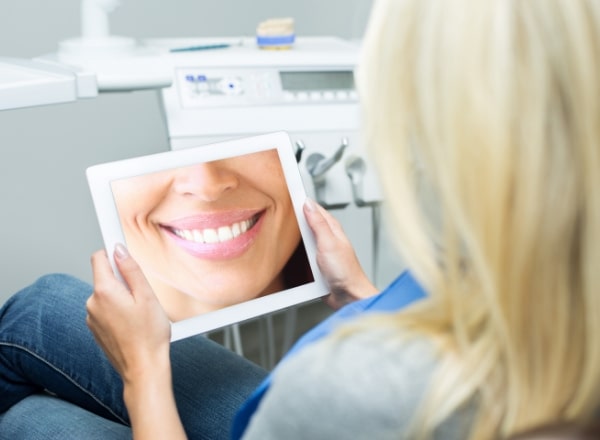 Woman looking at smile makeover sample on tablet computer