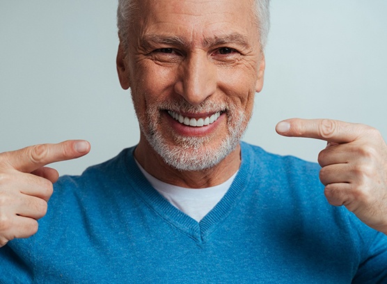 A handsome older an pointing at his new dentures