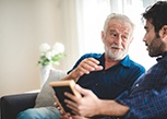 An older man talking on a cell phone while sitting on a park bench