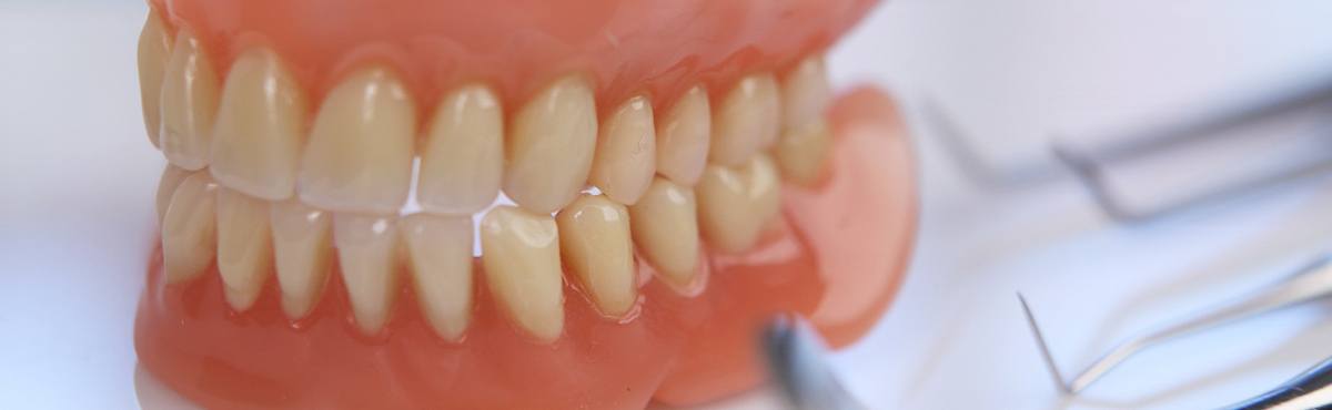 Close-up of full dentures in Phoenix, AZ next to dental instruments