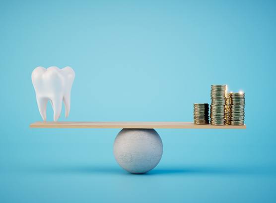 A model tooth and gold coins set on a balance beam