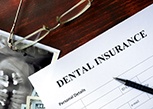 A dental insurance form set on a brown wooden table
