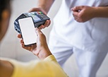 A patient using their phone to pay the cost of dentures 