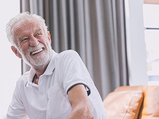Older man wearing a white shirt and smiling with dentures