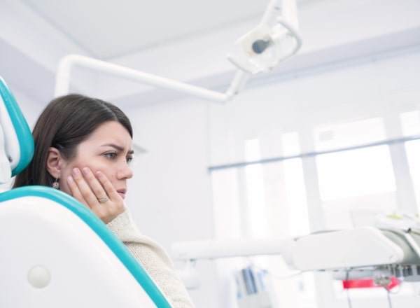 Dental patient in need of emergency dentistry holding cheek in pain