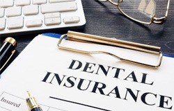 Dental insurance papers on clipboard on desk