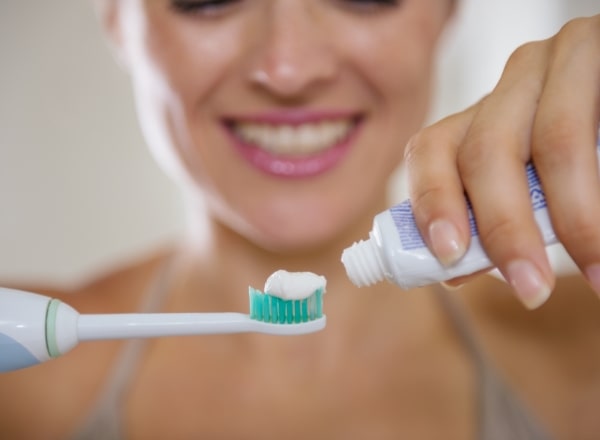 Woman brushing teeth before professional dental cleanings