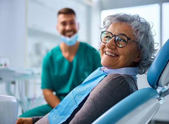 Woman with black glasses sitting in treatment chair