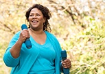 Smiling woman walking while lifting weights