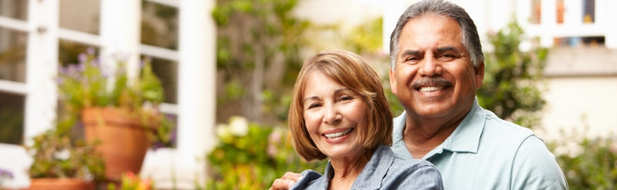 Man and woman with healthy smiles enjoying tooth replacement with dental implants