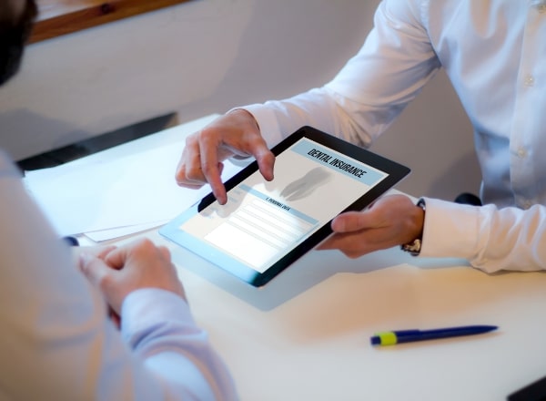 Dentist and patient looking at dental insurance forms on tablet computer