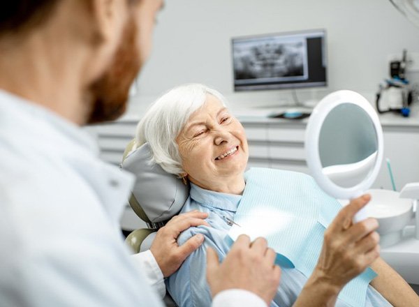 a patient checking her smile with a mirror