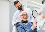 a patient checking her smile with a mirror