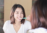 a woman happily brushing her teeth