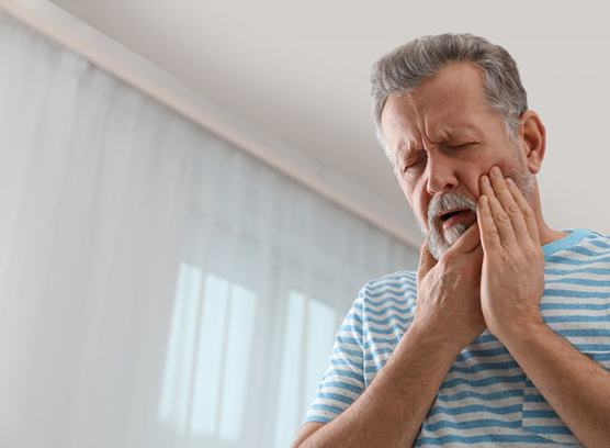 a man holding his cheek due to tooth pain
