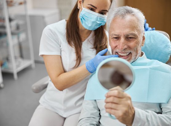 a patient checking his smile with a mirror