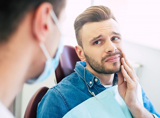 a patient holding his cheek due to tooth pain