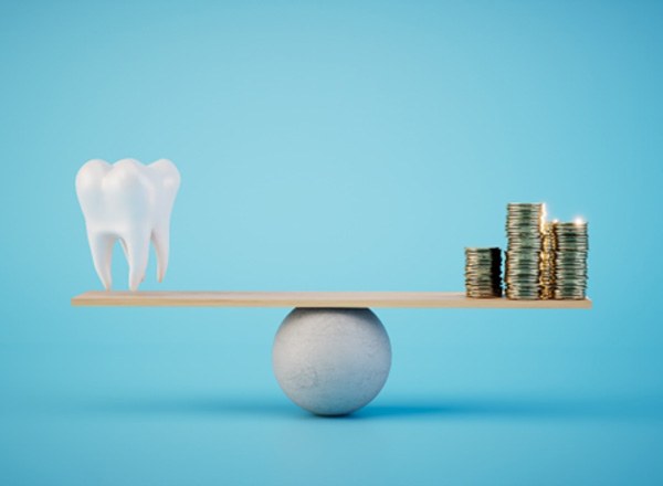 A large tooth and gold coins on a balance beam