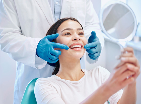 Patient smiling at reflection in handheld mirror
