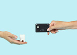 One hand holding model tooth and another offering black credit card with light blue background