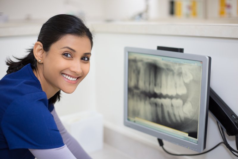 Smiling dentist with dental X-ray on a screen