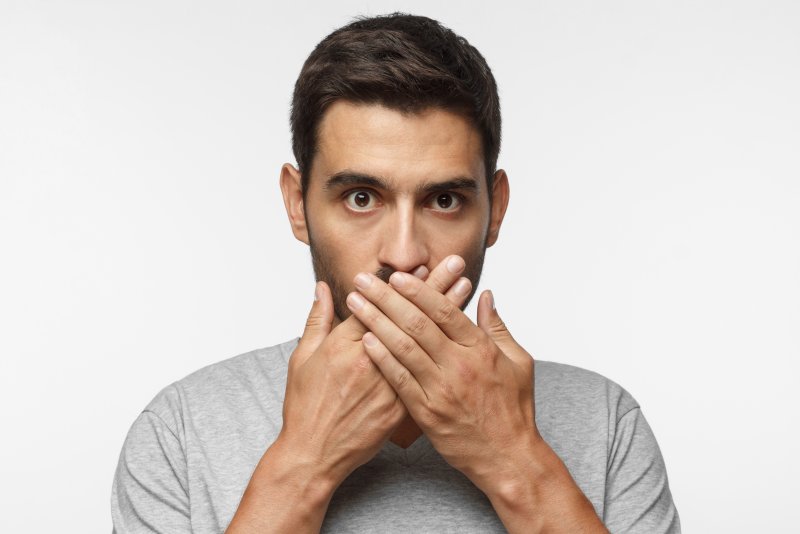 Man covering up gray teeth