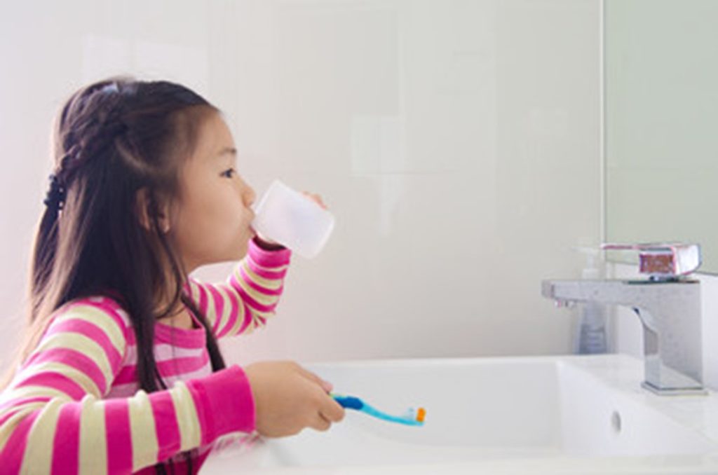Young girl rinsing her mouth after brushing her teeth.