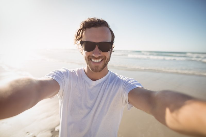 man smiling with veneers at the beach 