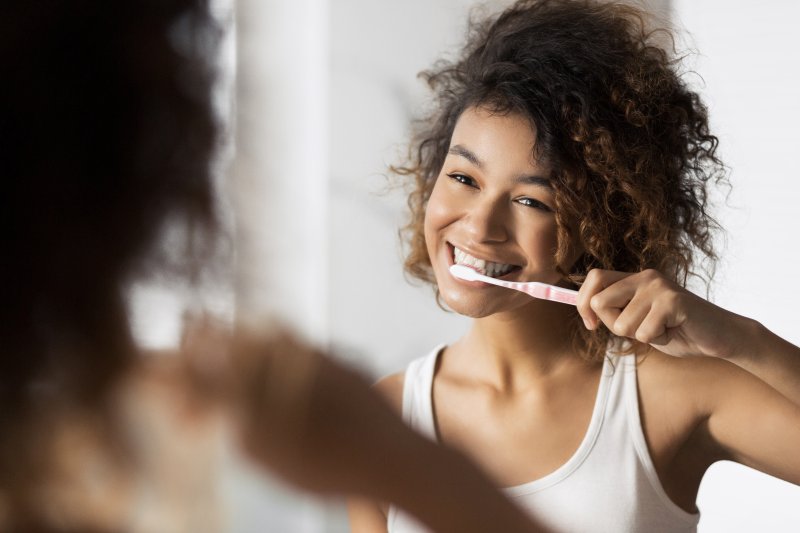 woman brushing teeth in bathroom mirror