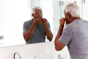 a person flossing while looking in the mirror