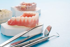 Set of dentures on a holder next to dental instruments