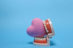 Set of false teeth biting a pink heart