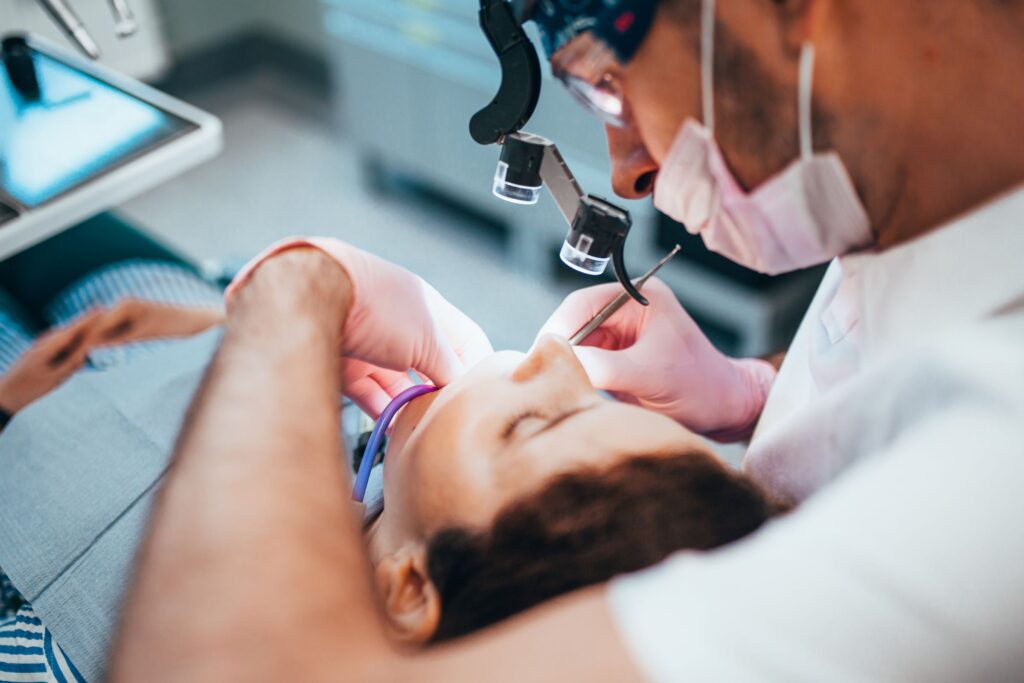 Dentist performing procedure with magnifying device