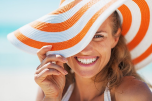 Woman smiling from under a large beach hat